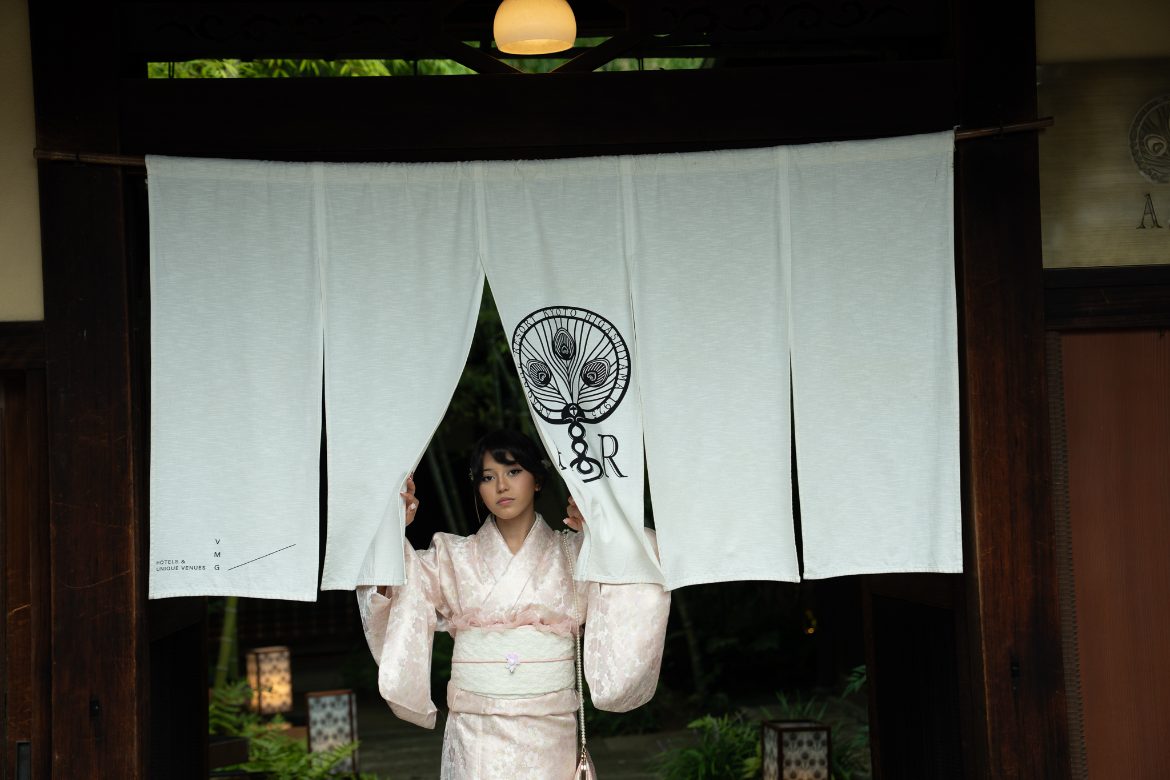 Arianna parting a white noren curtain in Kyoto